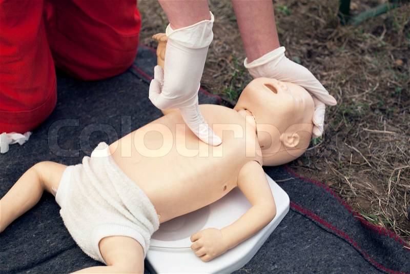 Paramedic demonstrates CPR on infant dummy, stock photo