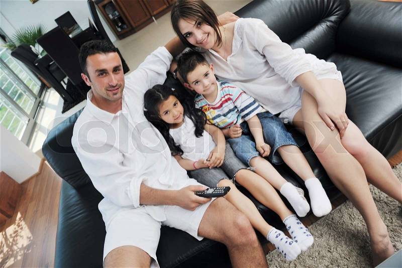 Happy young family wathching flat tv at modern home indoor, stock photo