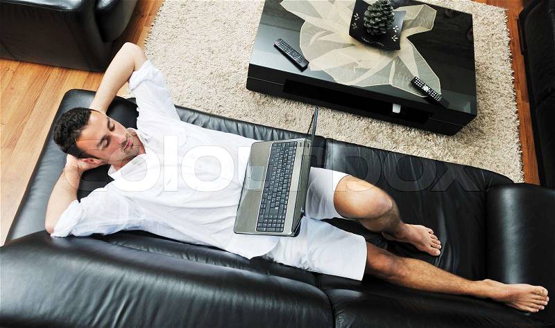 Portrait of a relaxed young guy using laptop at home indoor, stock photo