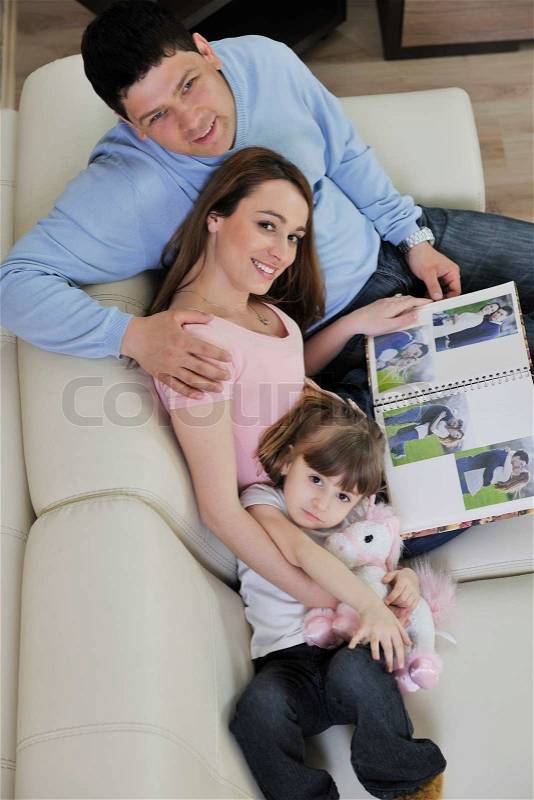 Happy young family looking old pictures in photo album at home, stock photo