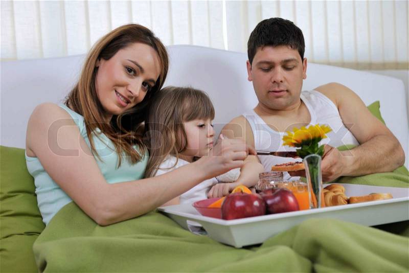 Happy young family eat breakfast in bed at morning, stock photo