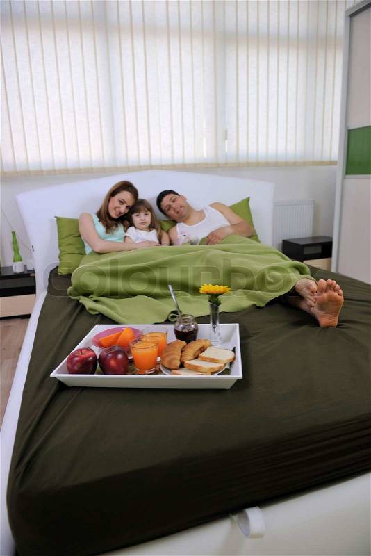 Happy young family eat breakfast in bed at morning, stock photo