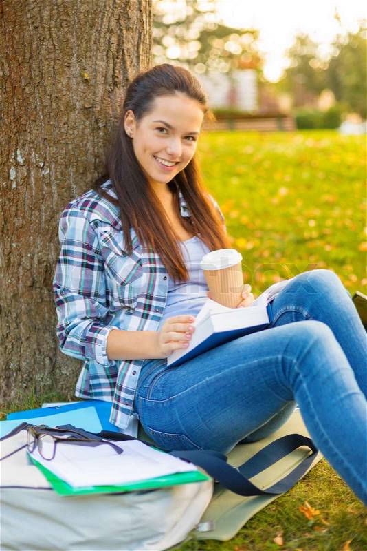 Education, campus and people concept - smiling teenager reading book with take away coffee, stock photo