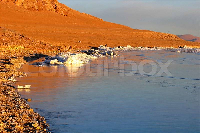 View of golden lakeside at sunrise in Tibet, stock photo