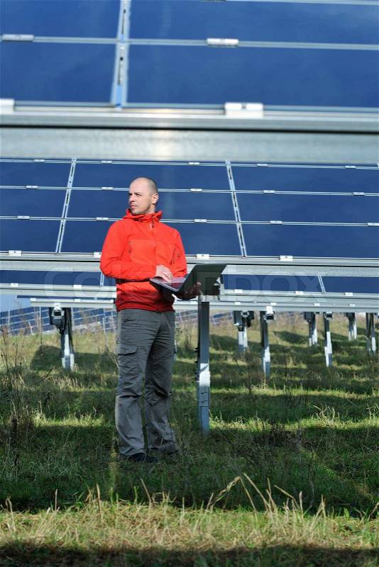 Business man engineer using laptop at solar panels plant eco energy field in background, stock photo
