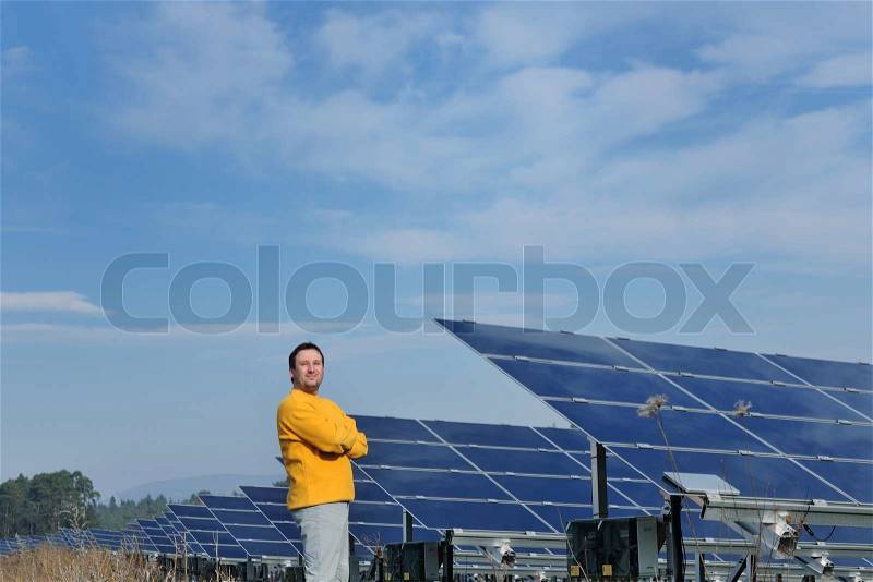 Male engineer at work place, solar panels plant industy in background, stock photo