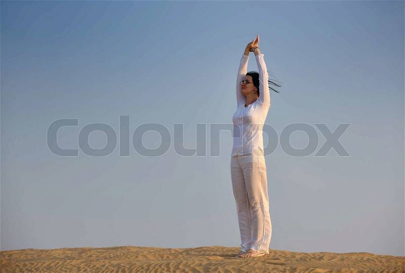 Happy young woman relax and exercise yoga at desert in sunset, stock photo