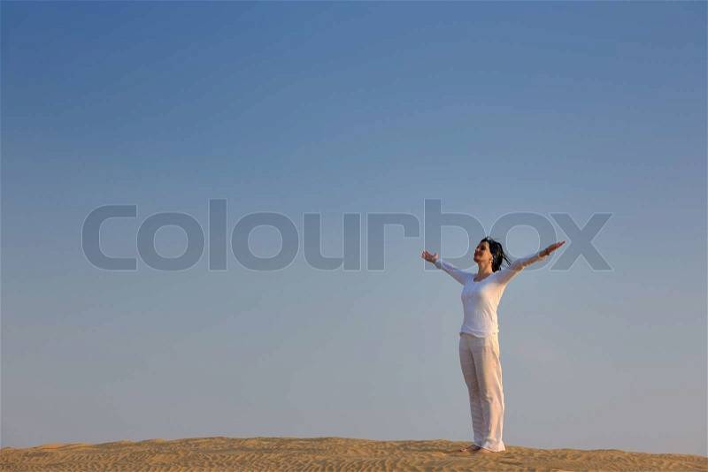 Happy young woman relax and exercise yoga at desert in sunset, stock photo