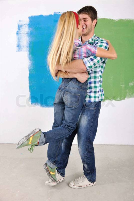 Happy young couple paint in green and blue color white wall of their new home, stock photo