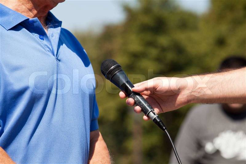 Journalist hand holding a microphone conducting an TV or radio interview, stock photo