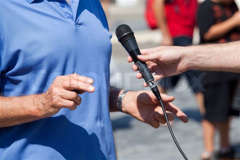 Journalist hand holding a microphone conducting an TV or radio interview, stock photo