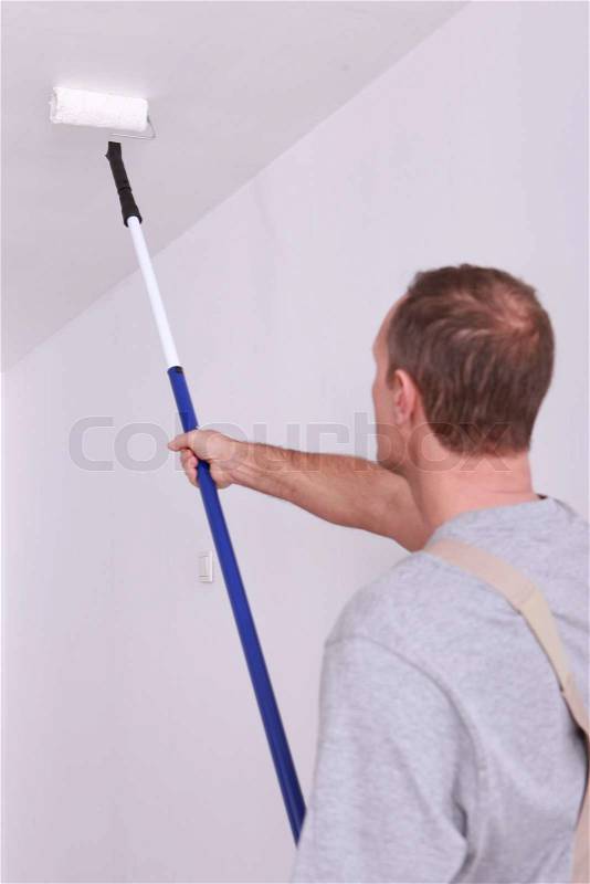 Decorator painting a ceiling white, stock photo