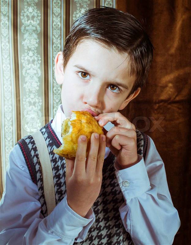 Child who eat donut. Vintage clothes and background, stock photo