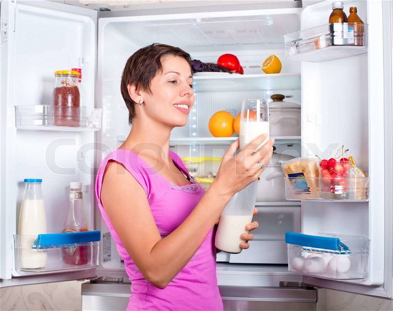 Young beautiful girl takes food from the refrigerator. Storing food in the refrigerator, stock photo