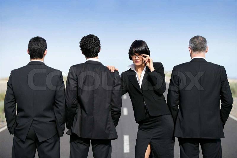 Woman in suit standing near men in suit, stock photo