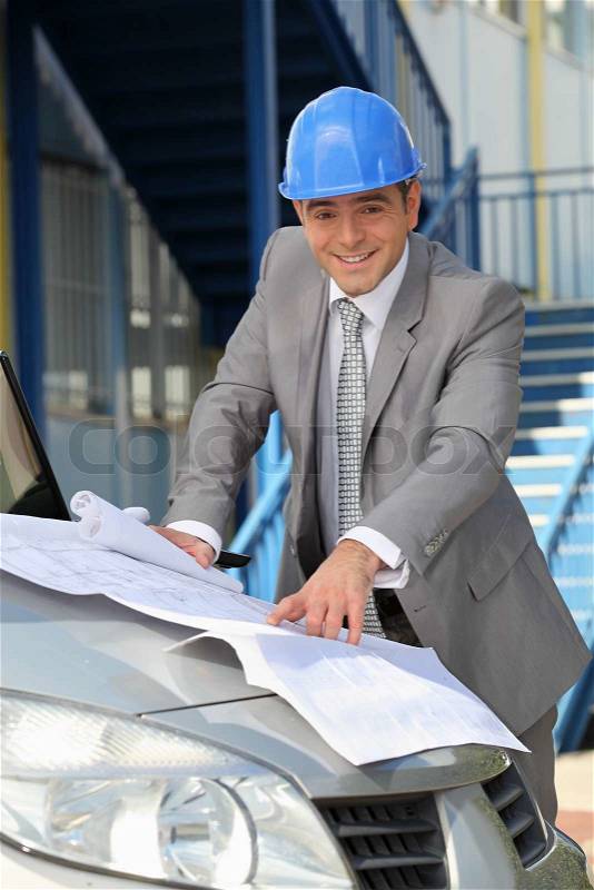 Architect looking at plans on a car bonnet, stock photo