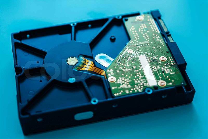 Computer hard drive on blue background (HDD, Winchester). Tilt-shift lens used to accent the center of the hdd and to emphasize the attention its central schemes, stock photo