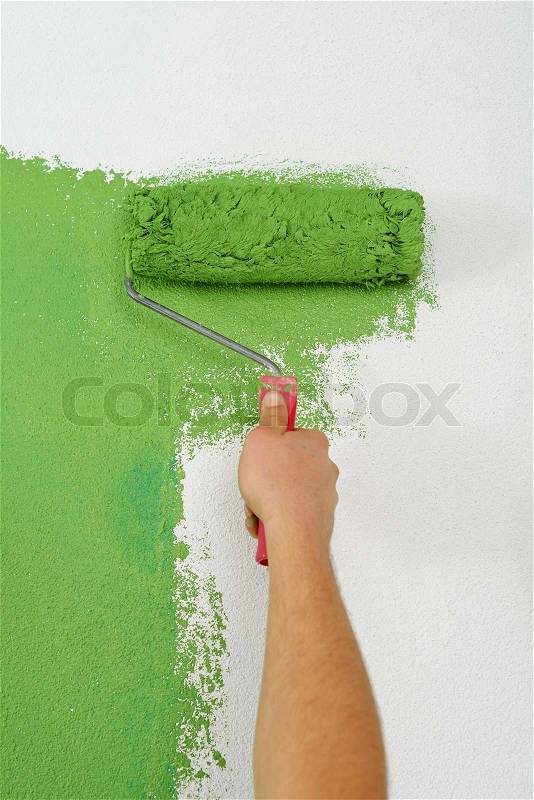 Handsome young man paint in blue and green color white wall of new home, stock photo