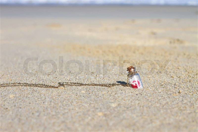 Small bottle in white sandy beach background the turquoise sea, stock photo