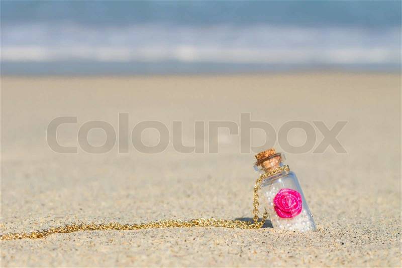 Small bottle in white sandy beach background the turquoise sea, stock photo