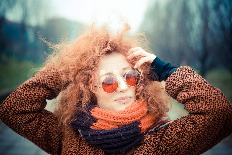 Young beautiful red curly hair woman with sunglasses at the park, stock photo