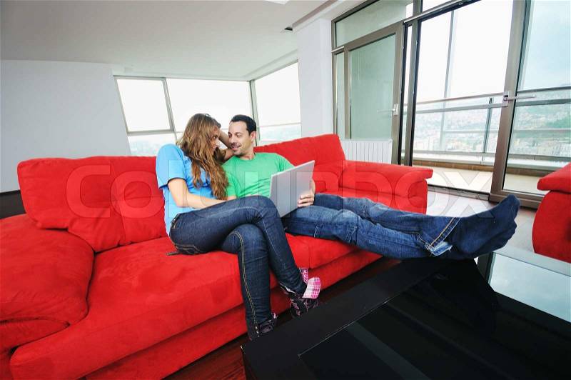 Happy young couple have fun and relax at comfort bright appartment and work on laptop computer, stock photo