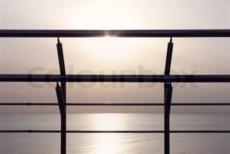 View on sunset and sea through fence, stock photo