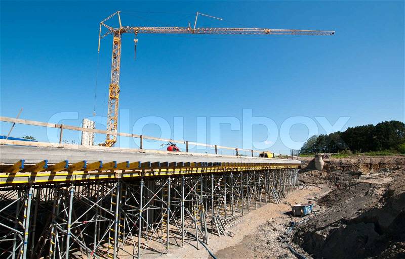 The construction of a new road bridge. Large construction site with crane and scaffolding, stock photo