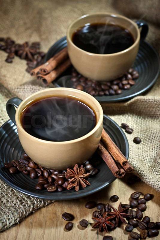 Two ceramic cups of coffee with cinamon and star anise on old coffee jute bugs, stock photo