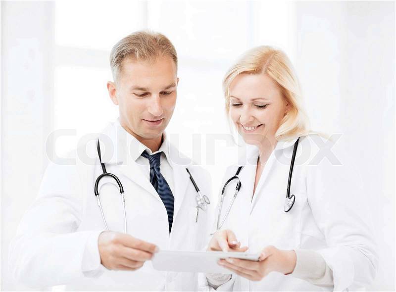 Healthcare and technology concept - two doctors looking at tablet pc, stock photo
