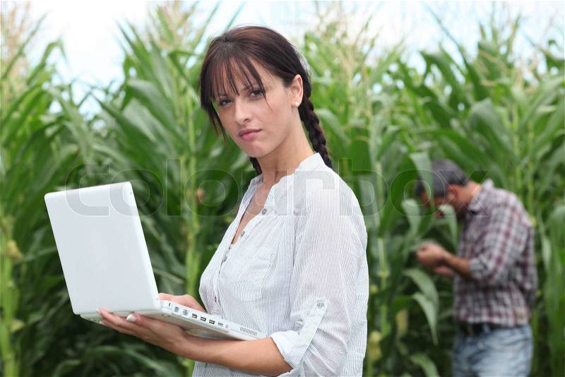 Farming couple with a laptop in a field of corn, stock photo