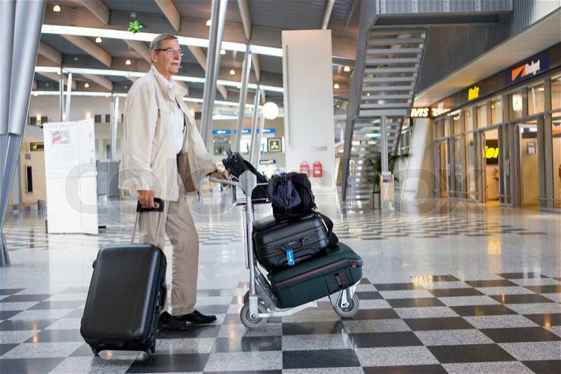 An elderly man lost at the airport with luggage, stock photo