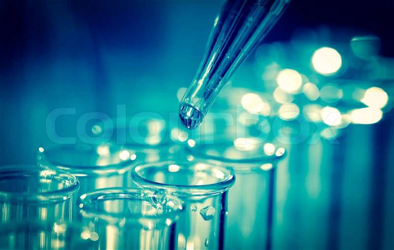 Pipette adding fluid to one of several test tubes, stock photo