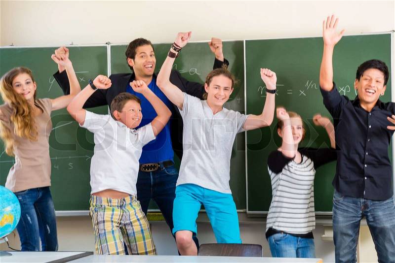 Successful Teacher and students jump in front of a blackboard with math work in a classroom or class school while lesson, stock photo