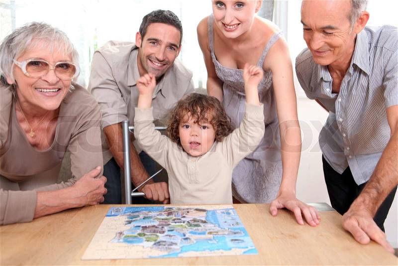 Family gathered around jigsaw puzzle, stock photo