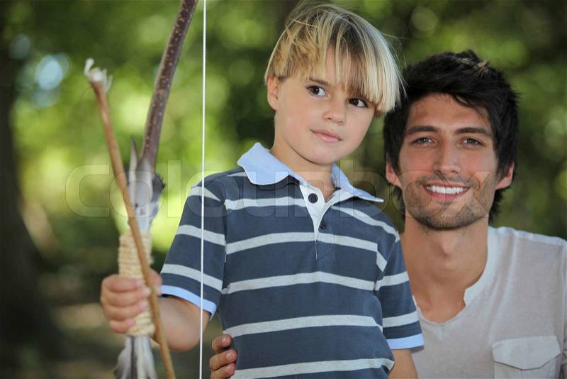 Father learning his son how to draw a bow, stock photo