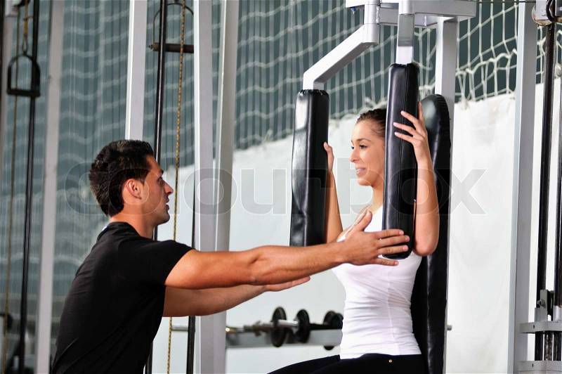 Woman in the fitness gim working out with personal trainer coach, stock photo