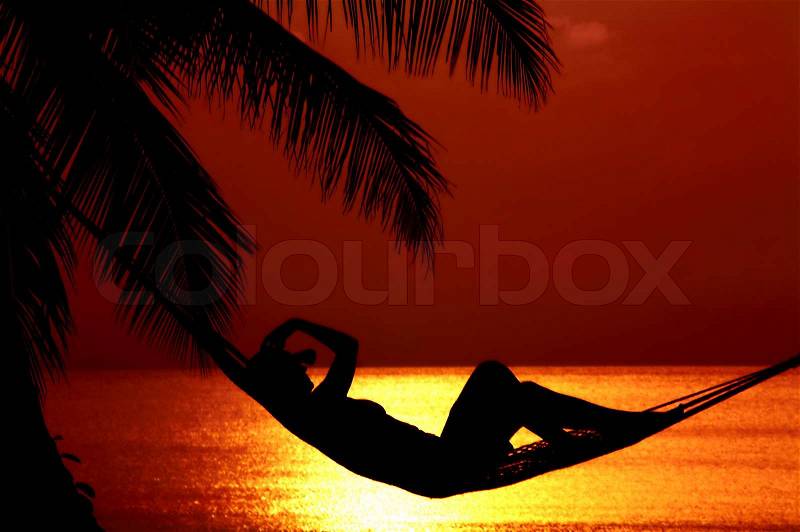 View of a woman lounging in hammock during sunset, stock photo
