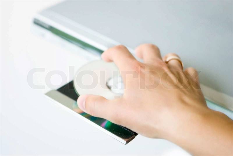 Cropped image of a hand inserting DVD to a dvd player, stock photo