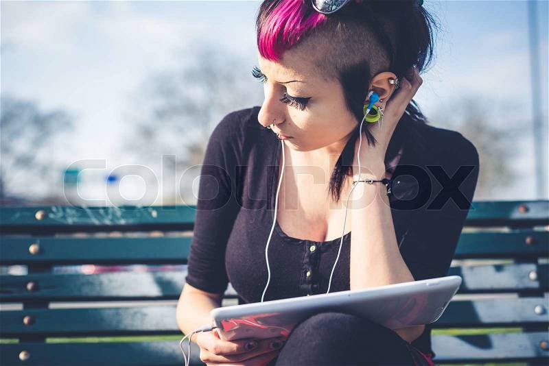 Young beautiful punk dark girl using tablet in urban landscape, stock photo