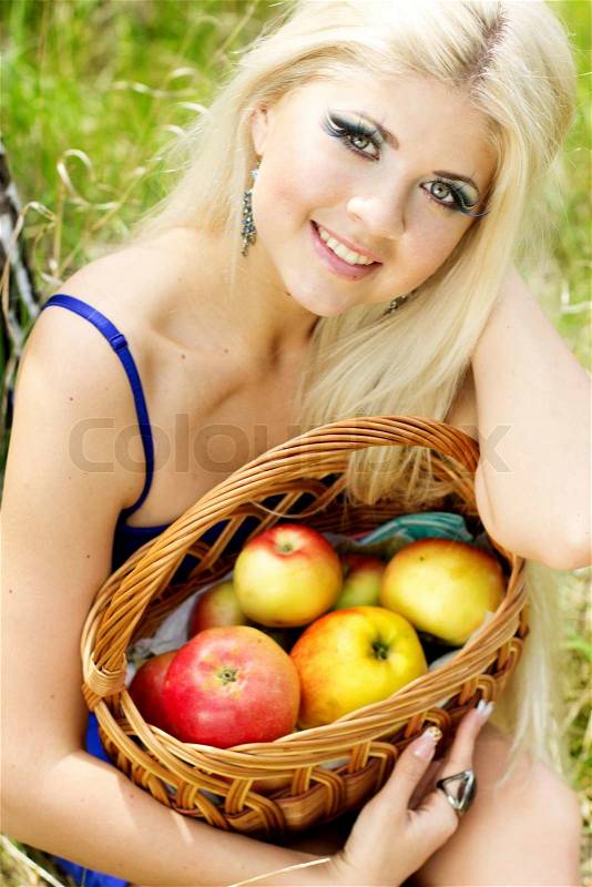 Spring time. Young woman with basket of apples, stock photo