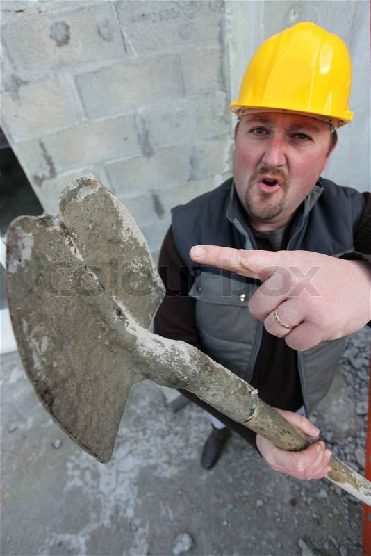 Tradesman pointing to a worn out spade, stock photo