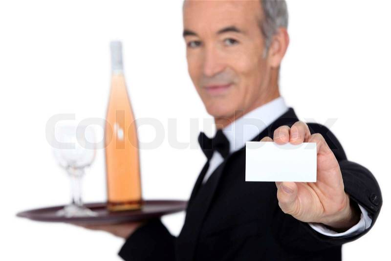 Waiter carrying bottle of wine with glass and showing his personal card, stock photo