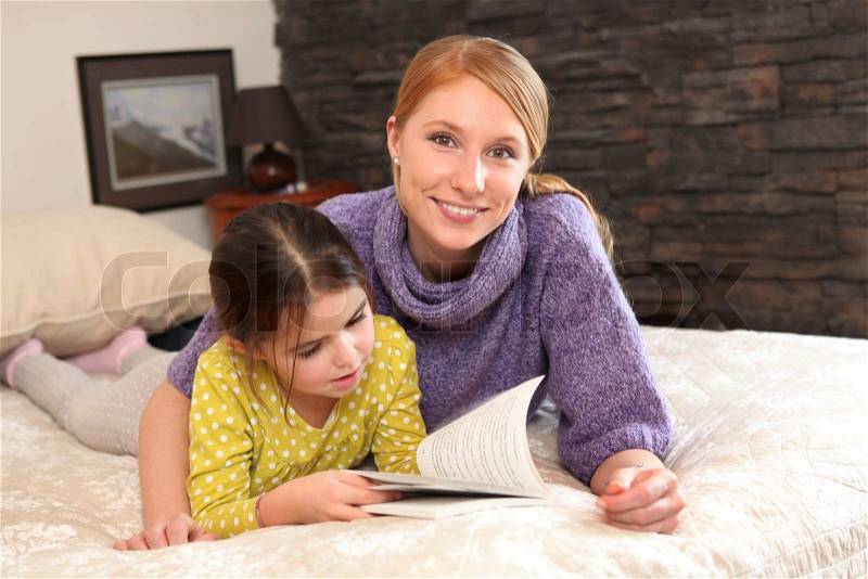 Mother and daughter reading together, stock photo