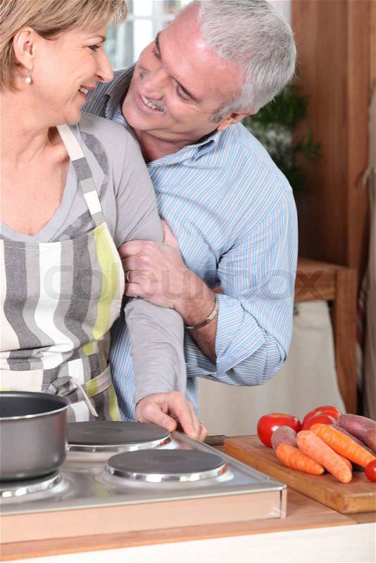 Smiling mature couple cooking, stock photo