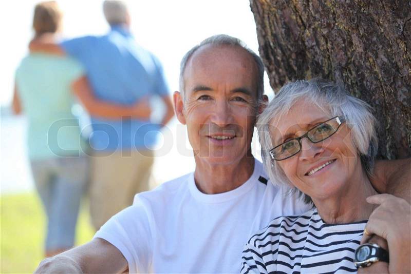 Relaxed older couple sitting in the shade of a tree on a summer\'s day, stock photo