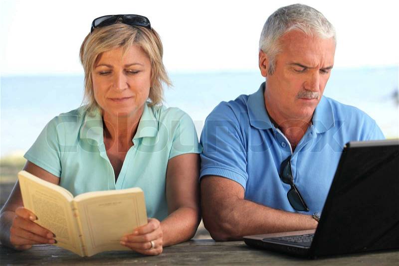 Young couple with book and computer, stock photo