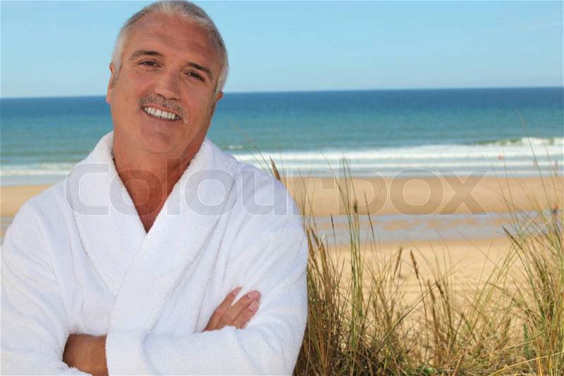 Man in bathrobe on beach, stock photo