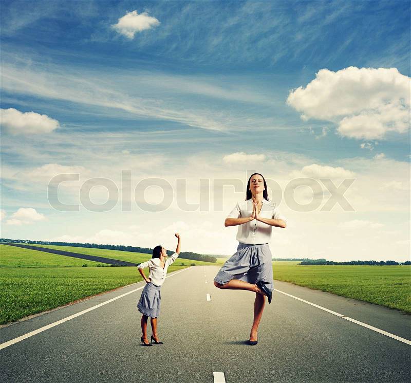 Emotional small woman and calm big woman standing on the road, stock photo