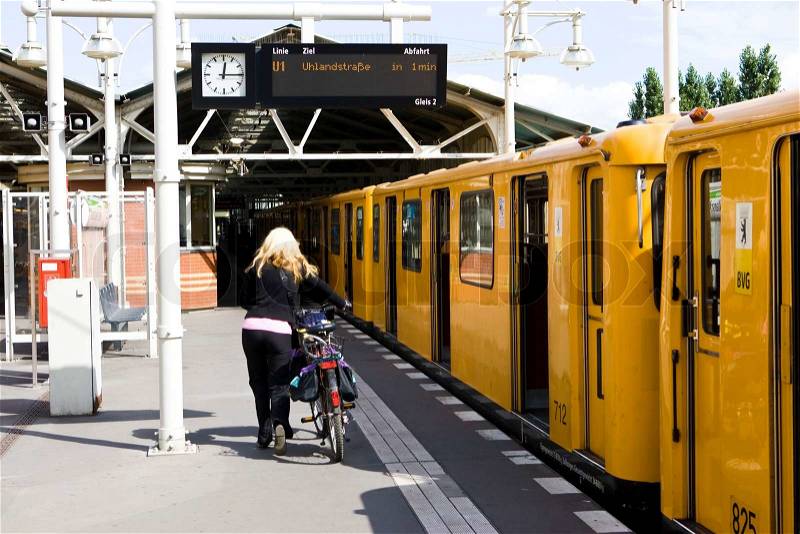 A woman walking with her bike in a train station, stock photo
